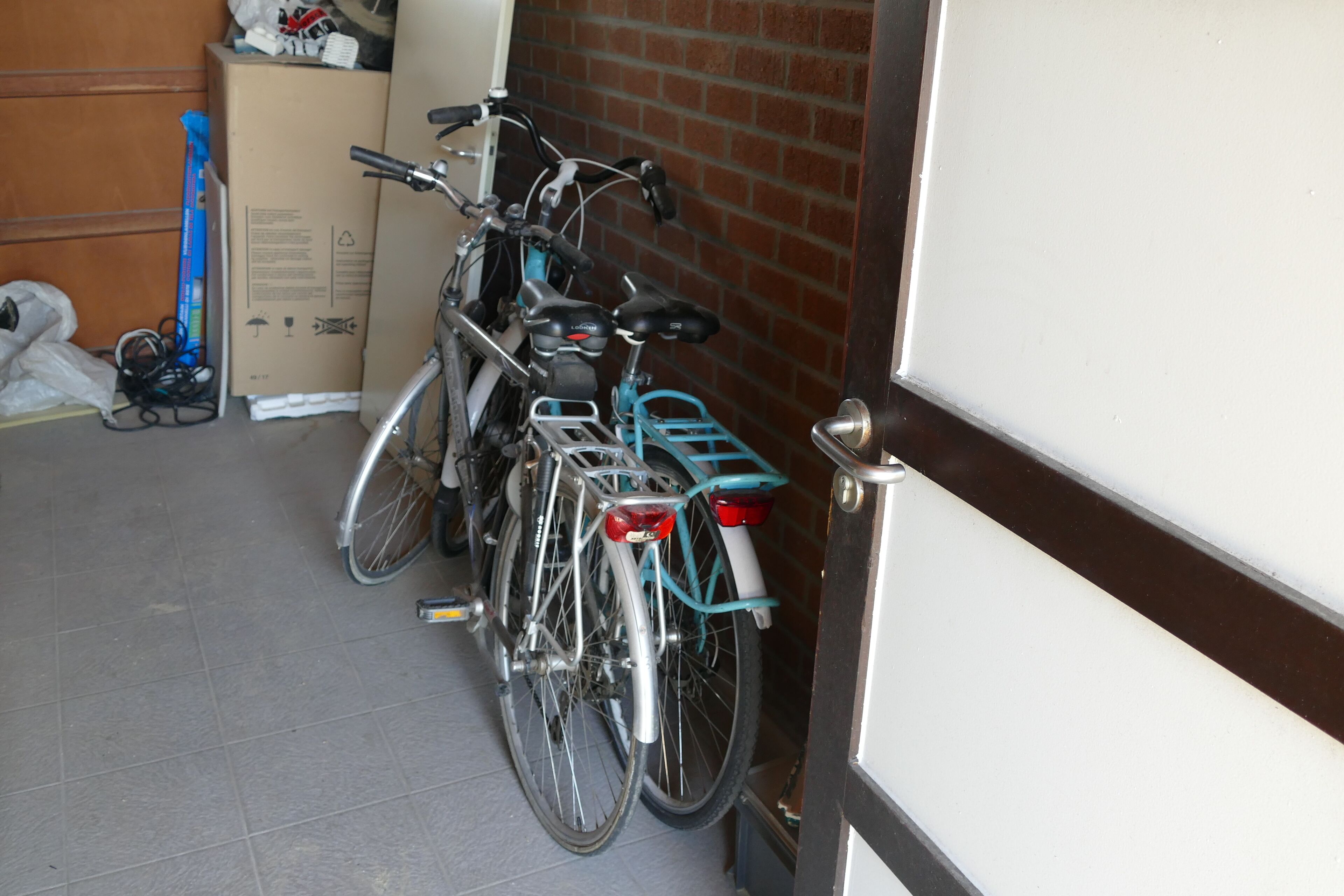 A bicycle parked in a garage with a brick wall and a door.