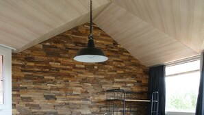 A bedroom with a sloped ceiling, a bunk bed, a hanging light fixture, and a window with curtains.