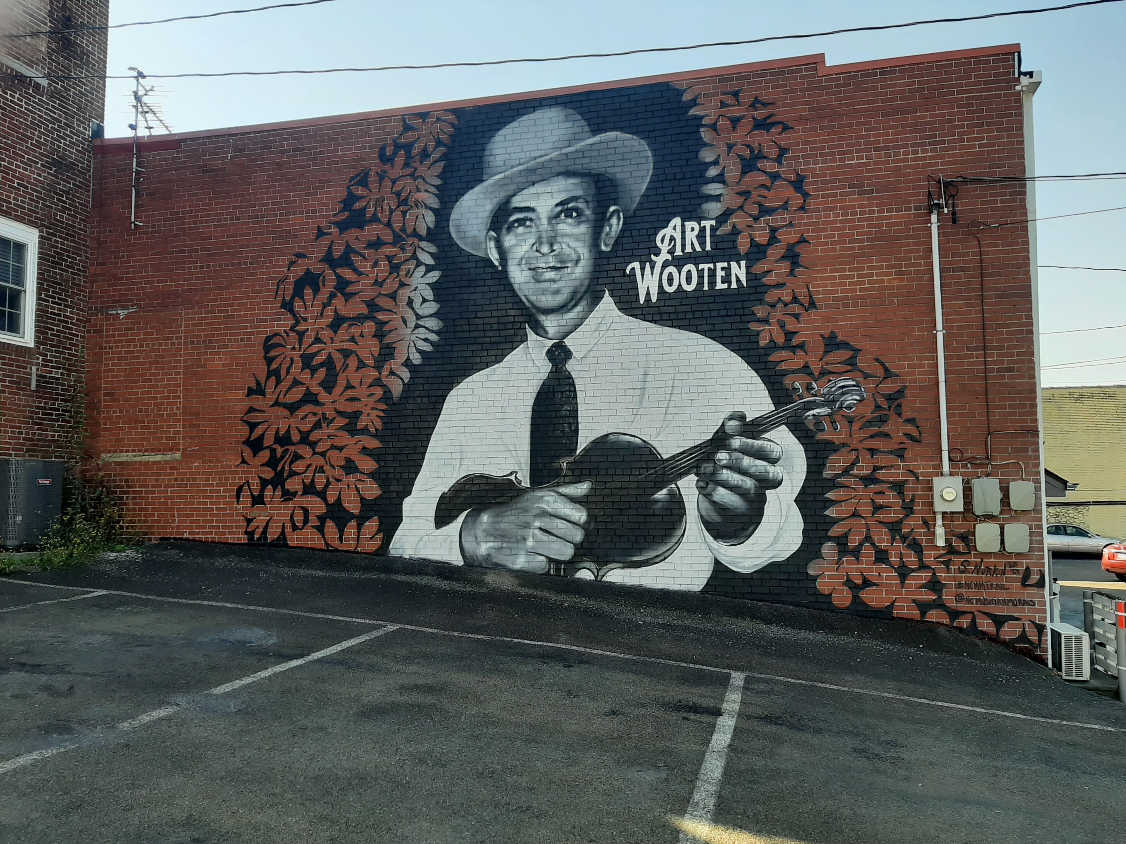 A mural of a man playing a guitar on a brick wall.