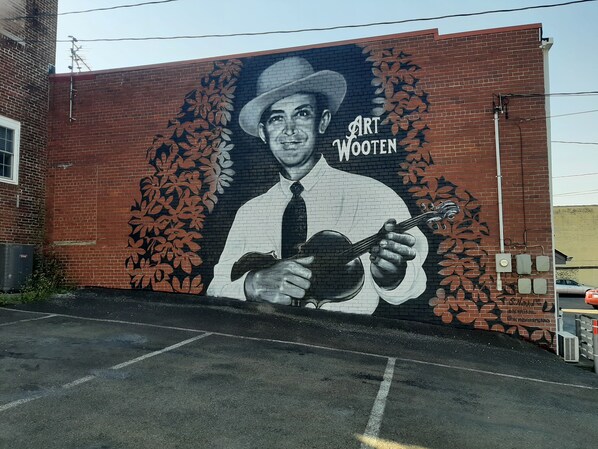 A mural of a man playing a guitar on a brick wall.