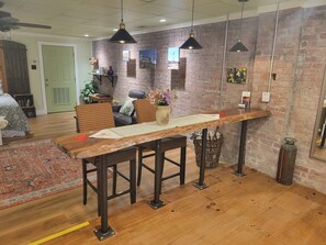 A dining area with a long wooden table, black metal chairs, and hanging pendant lights. - Downtown studio apartment walking distance to restaurants and shops (Sparta)