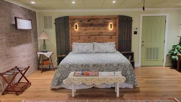 A bedroom with a bed, a nightstand, a lamp, a wooden headboard, a green door, and a patterned rug.