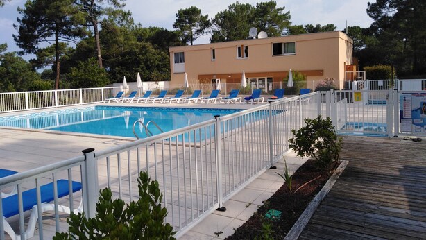 A swimming pool with lounge chairs and a white fence.