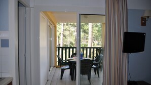 A room with a sliding glass door leading to an outdoor balcony with chairs and a table.