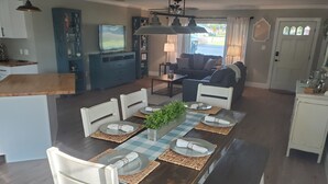 A dining area with a wooden table set for four, surrounded by white chairs.