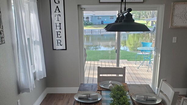 A dining area with a dark wooden table set for four, a view of a backyard with a pool, and a 'Gather' sign on the wall.