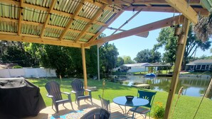 A covered outdoor deck with a wooden pergola, a barbecue grill, and outdoor furniture.