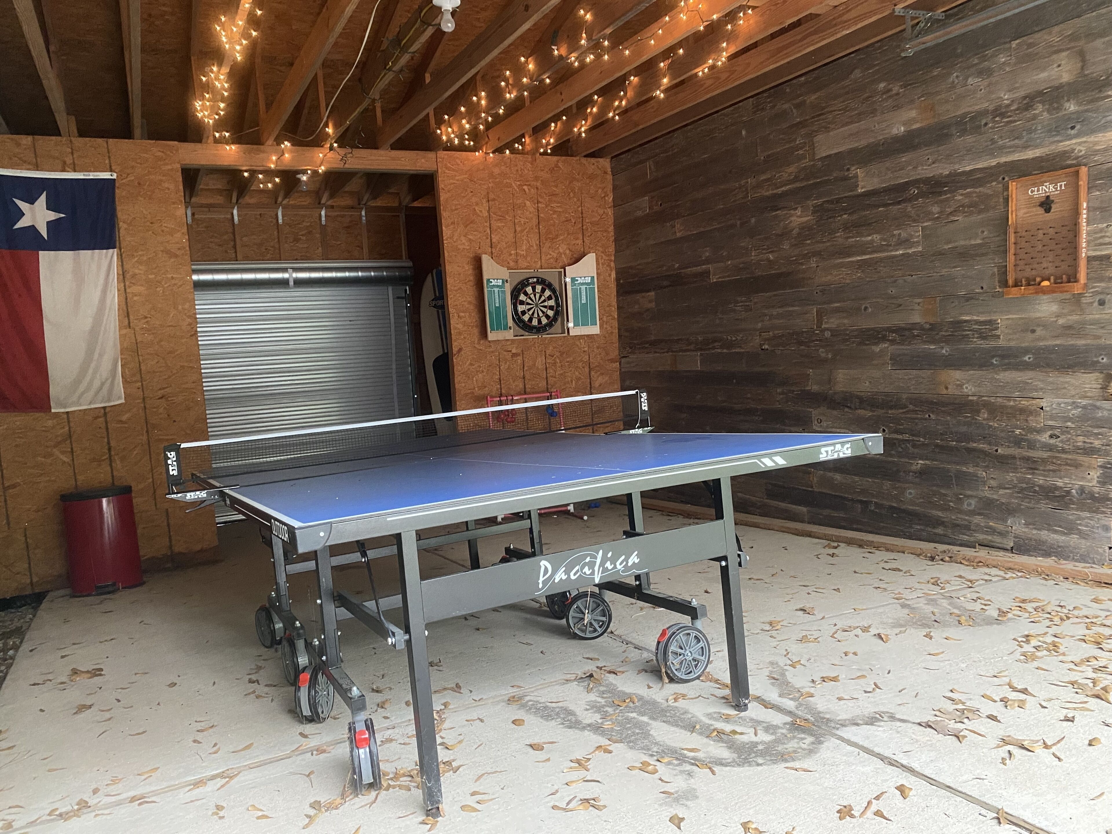 A ping pong table in a rustic room with wooden walls and a Texas flag.
