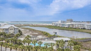 A coastal hotel with a pool, beachfront view, and a pier in the background.