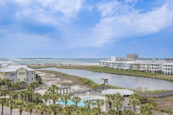 Un hôtel situé sur la côte, doté d’une piscine, offrant une vue sur la plage et avec une jetée en arrière-plan.