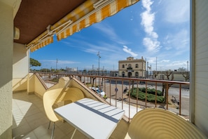Enjoy the view from this balcony with a table and two chairs, overlooking the street scene below.