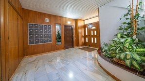 Eine Lobby mit Holzwänden, einem Marmorboden, einer Pflanzengestaltung und einem Empfangstresen.