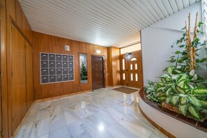 Welcome to the lobby, featuring a wooden panel wall, marble floor, and a large potted plant.