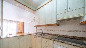 Eine Küche mit hellen Holzschränken, einer Granit Arbeitsplatte, einer Spüle mit zwei Becken und einem eingebauten Herd.
