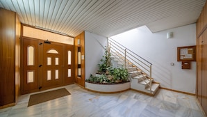 Ein geräumiger Eingangsbereich mit Holztür, Treppe und einem kleinen Innenhof.
