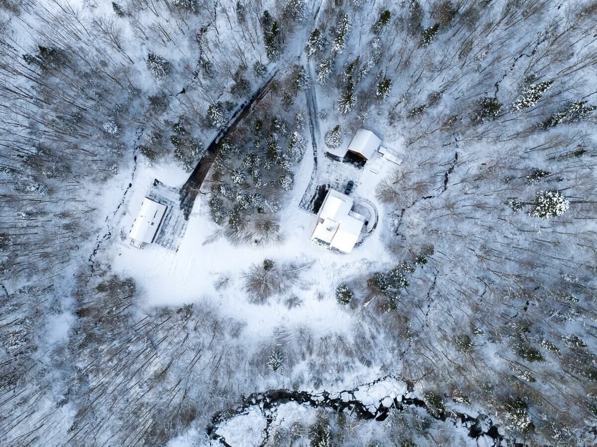 Vue aérienne d’une zone enneigée avec un petit bâtiment et une structure blanche.