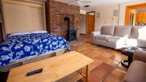 Una habitación acogedora con cama, sofá, mesa y chimenea.