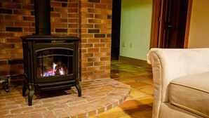 Una habitación con chimenea de ladrillo, un sofá color crema y piso de baldosas.