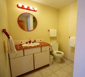 Een badkamer met een wastafel, spiegel en toilet.