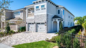 A two-story house with a stone facade, a front porch, and a driveway leading to a garage. - Sophisticated Villa with Movie Room at Encore (Kissimmee)