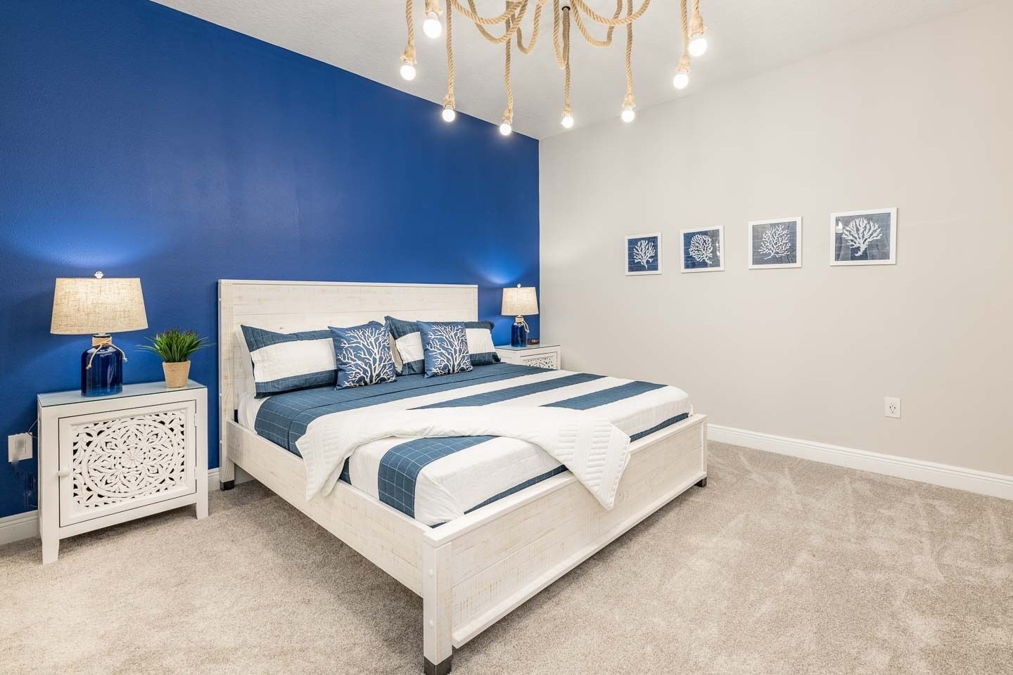 A bedroom with a bed, nightstands, a chandelier, and wall art.