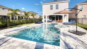 A swimming pool with a hot tub, surrounded by a patio area with seating and a covered section. - Sophisticated Villa with Movie Room at Encore (Kissimmee)