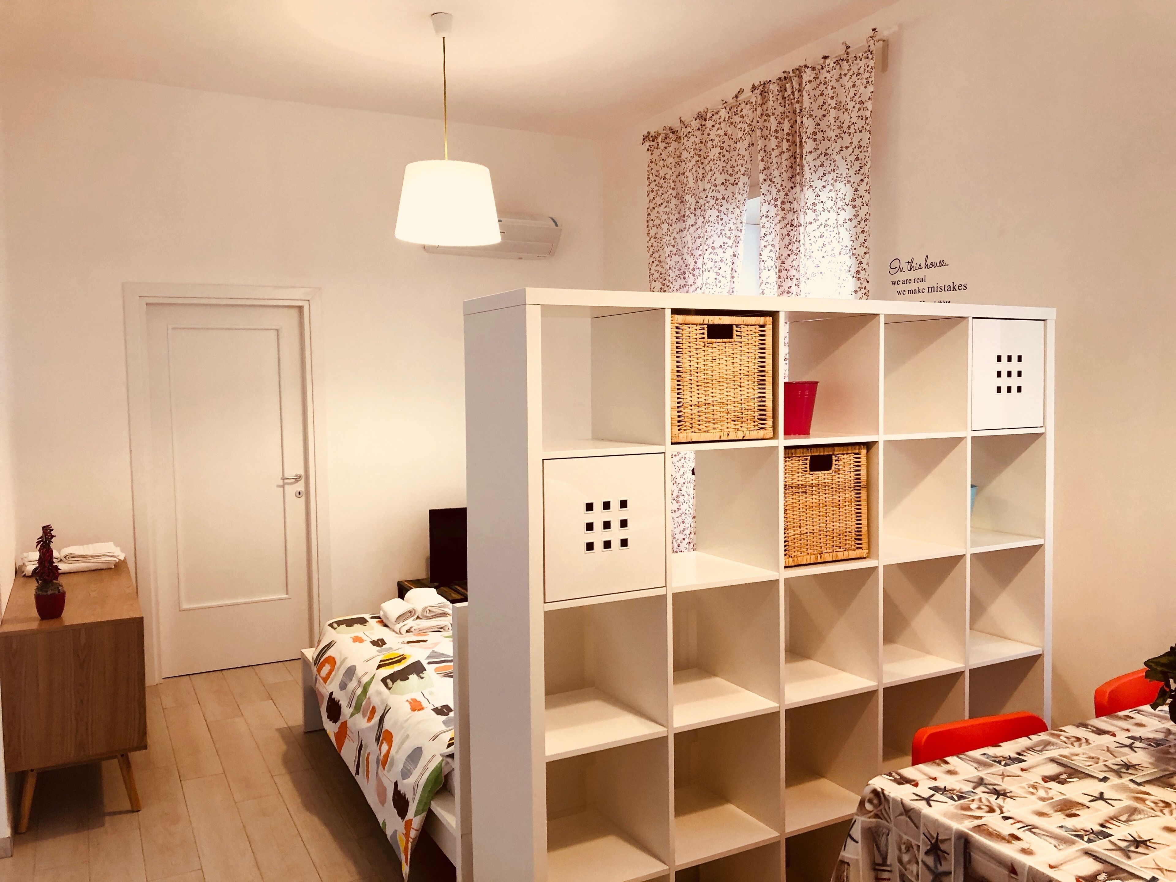 Ein Schlafzimmer mit einem Bett, einem Schreibtisch, einem Stuhl, einem Kleiderschrank und einem Tisch mit Tischdecke.