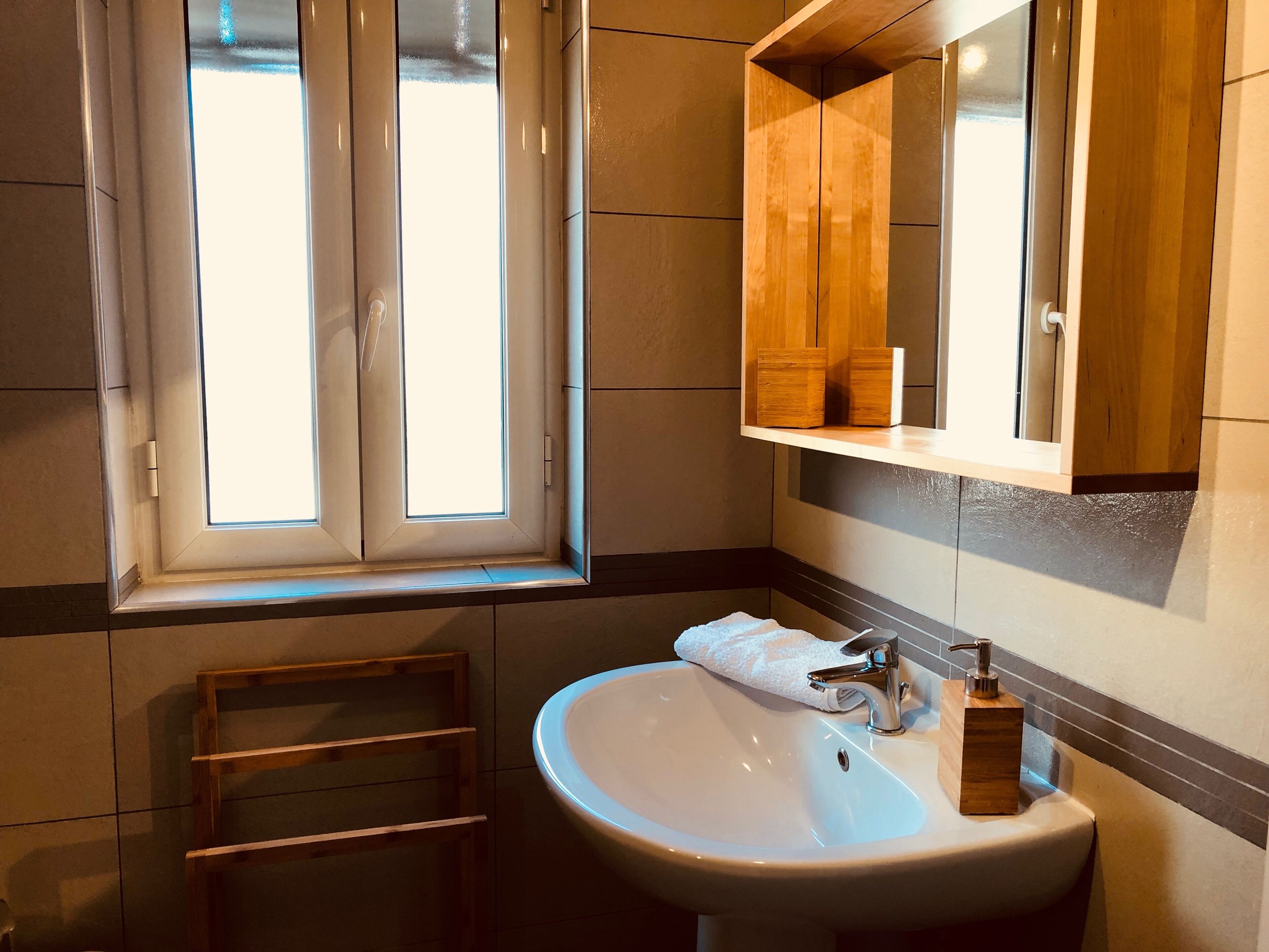 Ein Badezimmer mit Fenster, Waschbecken und Holzschrank.