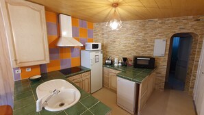 Uma cozinha compacta com pia, micro-ondas e torradeira.
