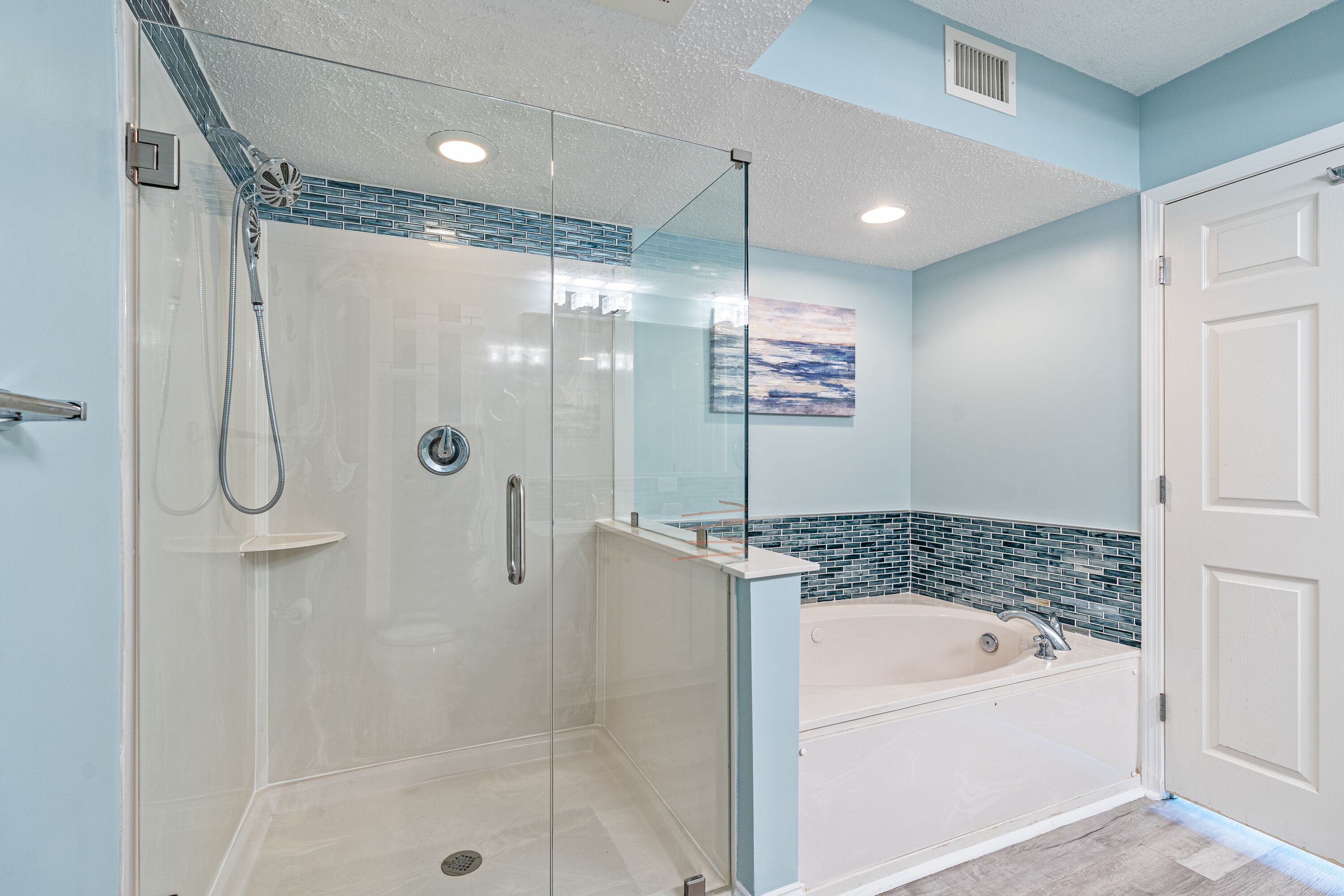 A modern bathroom with a glass-enclosed shower, a freestanding bathtub, and a tiled backsplash.