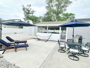 An outdoor patio with lounge chairs, a table, and umbrellas. - Hot Tub Outdoor Oasis by Country Road Properties (North Cape May)