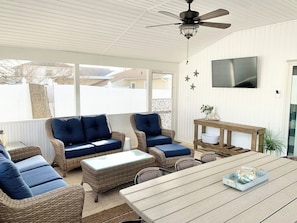 A covered patio with wicker furniture, a wooden table, and a ceiling fan. - Hot Tub Outdoor Oasis by Country Road Properties (North Cape May)