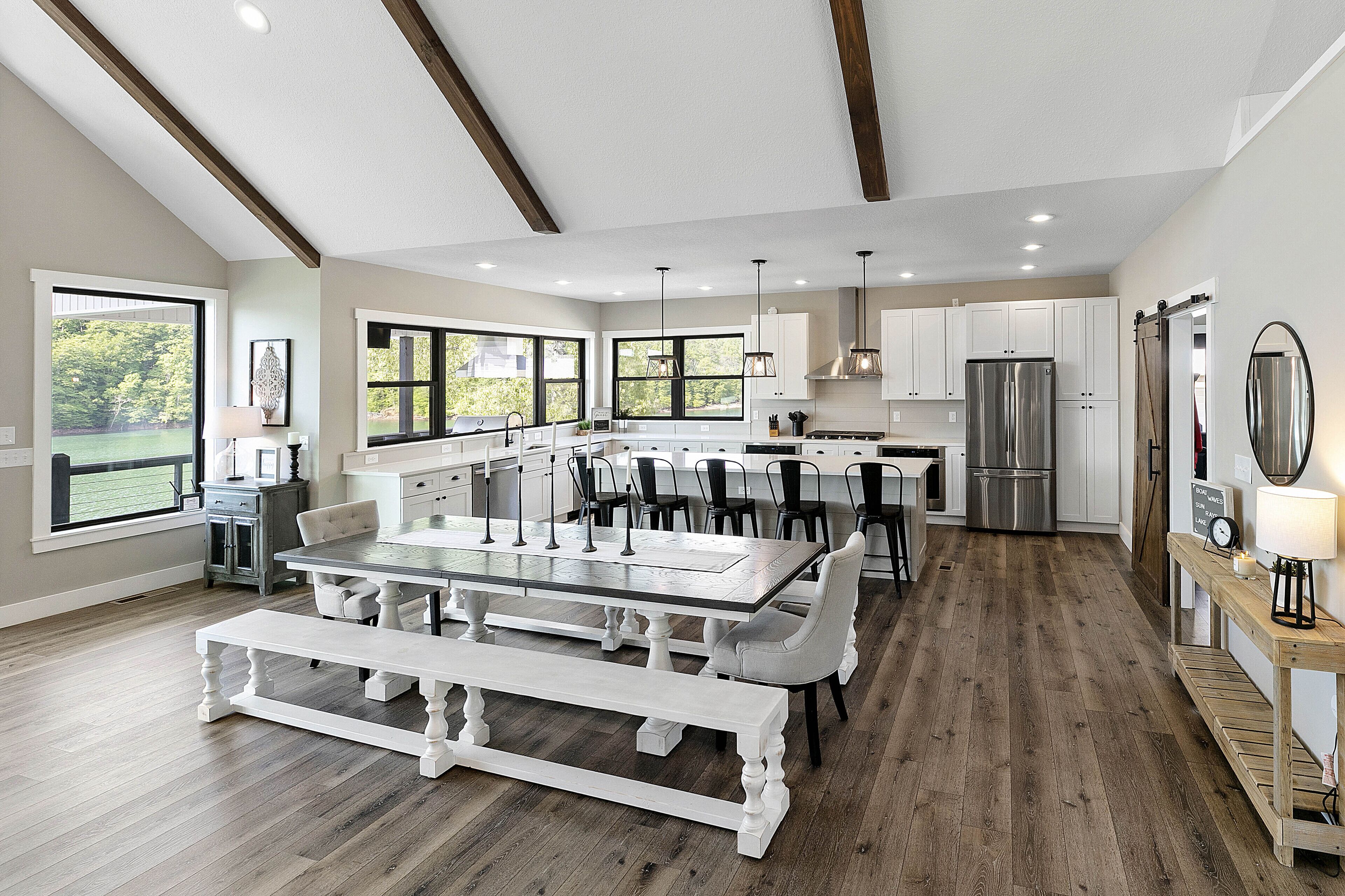 A spacious kitchen with a central island, white cabinetry, and a large window overlooking a green landscape.