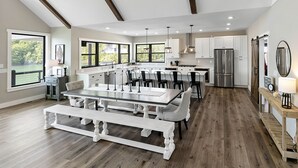 A spacious kitchen with a central island, white cabinetry, and a large window overlooking a green landscape.