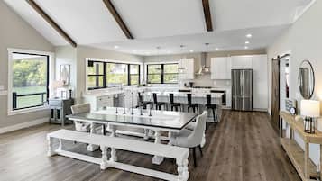 A spacious kitchen with a central island, white cabinetry, and a large window overlooking a green landscape.