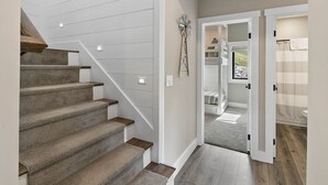 A staircase with carpeted steps and wooden handrails, leading to a room with a view of the outdoors.