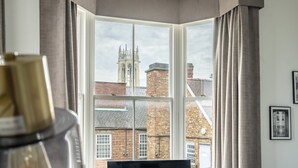 Ein Zimmer mit Erkerfenster und Blick auf ein historisches Gebäude, sowie ein schwarzer Sessel.