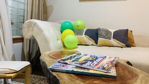 A living room with a sofa, a coffee table with magazines, and balloons. - Central Stylish Home (Accra)