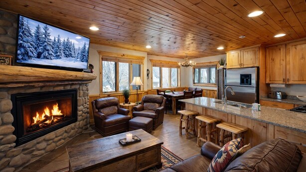 Una sala de estar acogedora con chimenea, muebles de cuero y revestimiento de piedra.