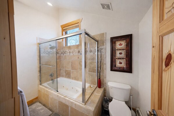 A bathroom with a glass-enclosed shower, a white toilet, and a framed picture on the wall.