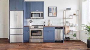 A modern kitchen with blue cabinets, stainless steel appliances, and a white tiled backsplash. - Large, Charming historic flat, Downtown/Bourbon trail/Yum Center (Louisville)
