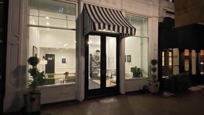 A two-story building with large windows and a striped awning at the entrance. - Large, Charming historic flat, Downtown/Bourbon trail/Yum Center (Louisville)