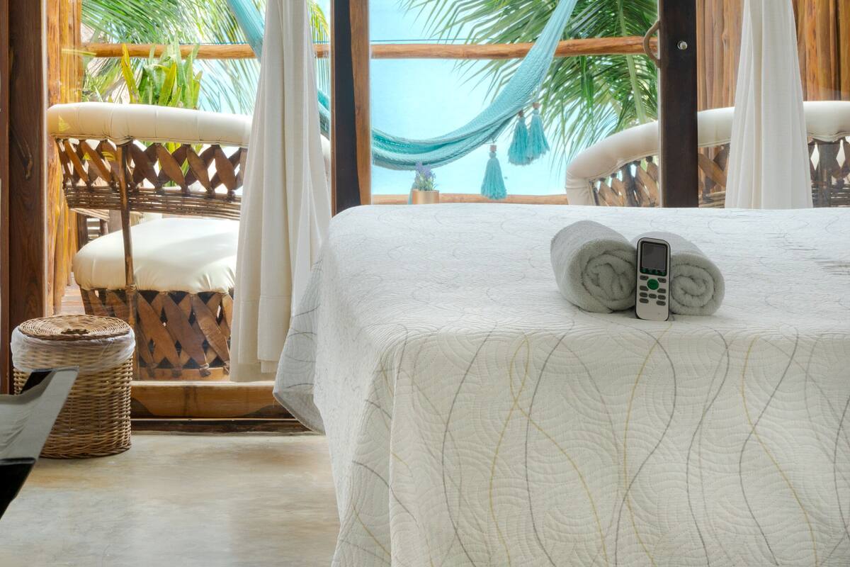 A room with a bed, a hammock, and a view of a pool.
