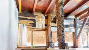 Eine rustikale Küche mit Holzbalkendecke, einem roten Kühlschrank, einem gewebten Korb und einem Fenster mit Vorhängen.