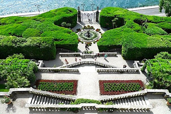 A symmetrical garden with a central fountain, pathways, and statues.