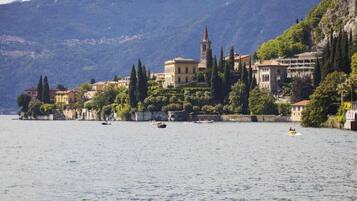 A lakeside town with historic buildings, a prominent church tower, and a clear view of the surrounding mountains.