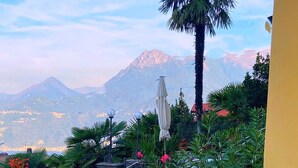 A patio with two lounge chairs, a stone pathway, and a view of mountains. - VILLA SILVANA - DOUBLE ROOM WITH LAKE VIEW (PERLEDO)