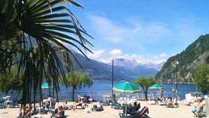 Une plage avec des chaises longues, des parasols et une chaîne de montagnes en arrière-plan.