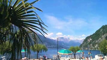 A beach with sun loungers, umbrellas, and a mountainous backdrop.