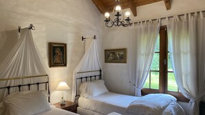 Una stanza con due letti, un lampadario e una finestra con tende.